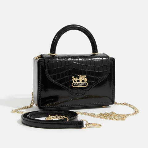 Black handbag with gold chain on a white background