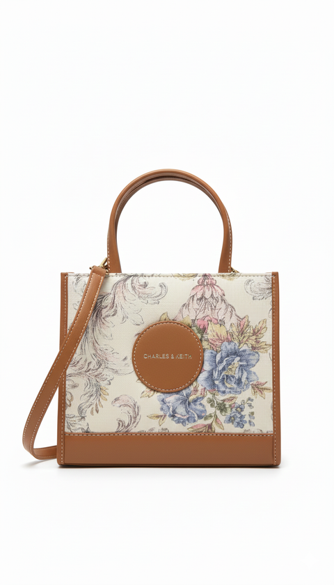 Floral-patterned handbag with brown leather accents on a white background