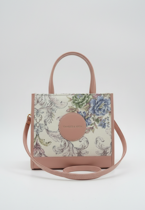 Floral patterned handbag with a pink strap on a white background