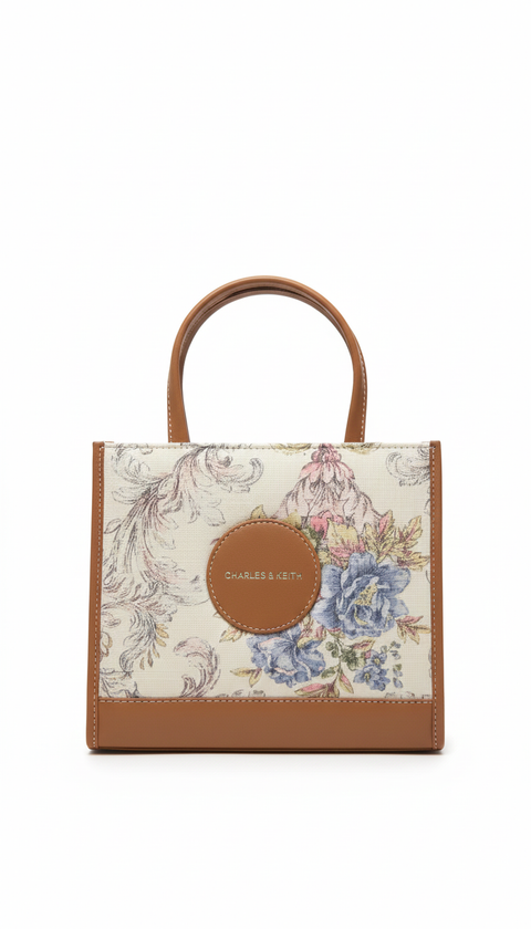 Small tote bag with floral pattern and brown handle on a white background