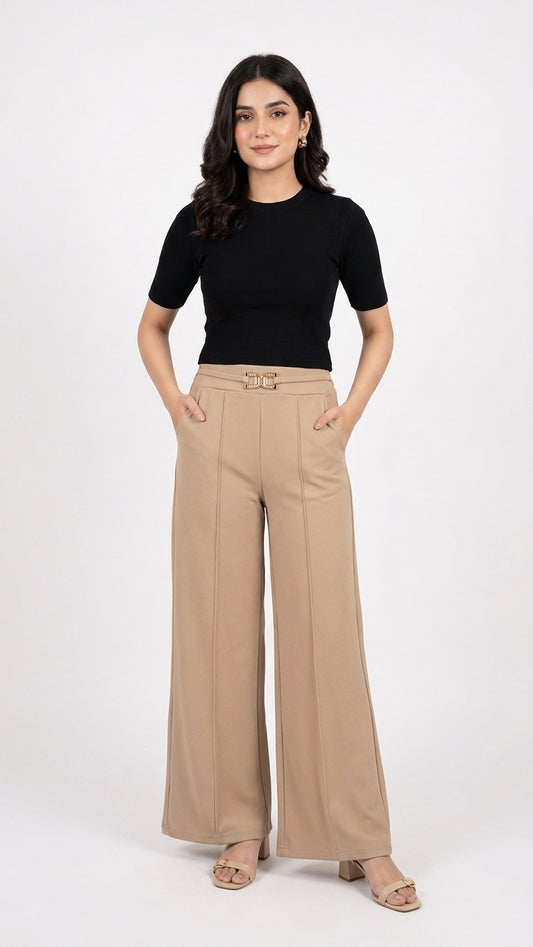 A woman modeling a black short-sleeve top and beige wide-leg trousers with a matching belt, standing against a plain white studio background.